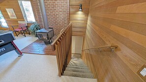 Staircase with a cozy landing area featuring a wood-burning stove and a simple layout.