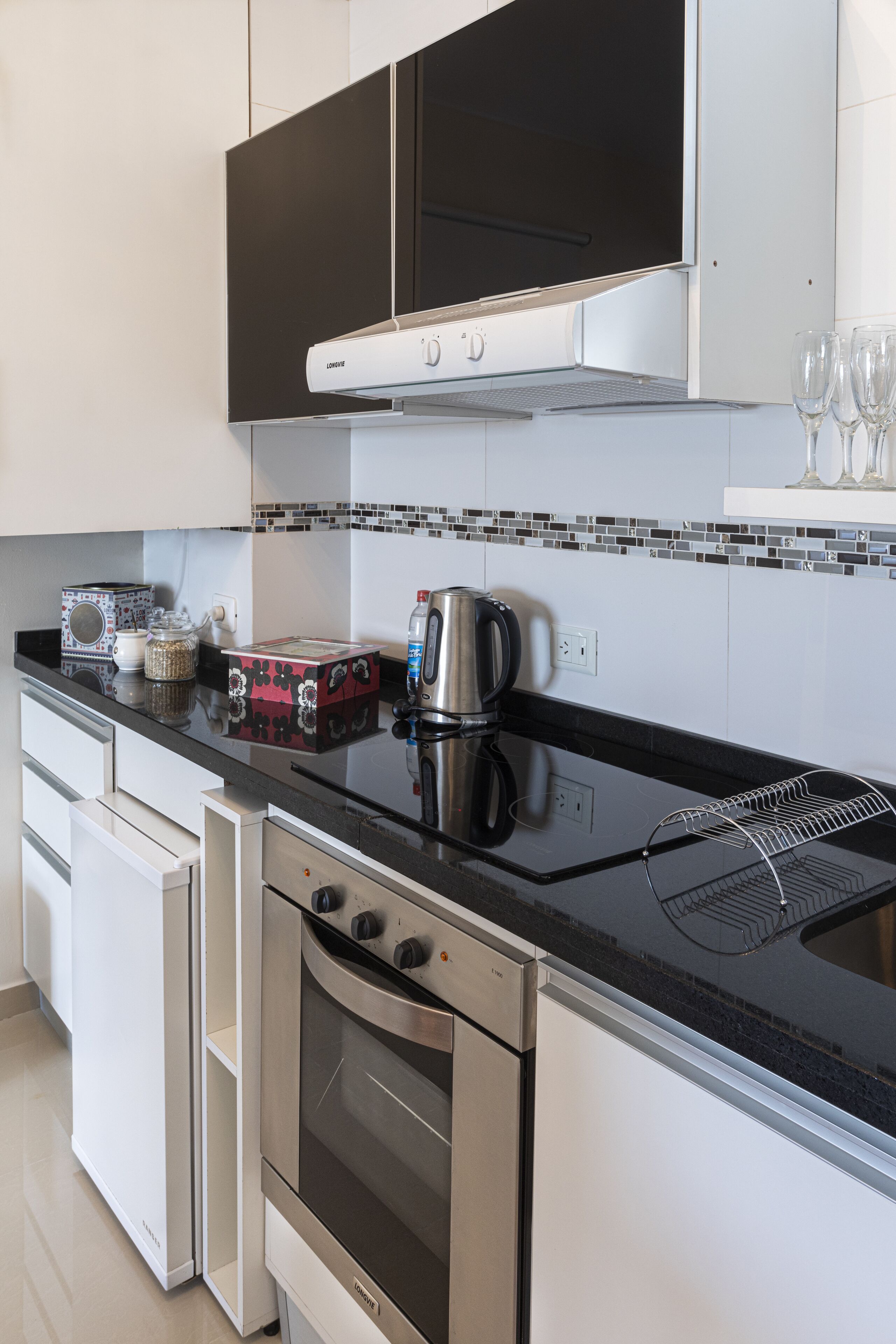Una cocina moderna con electrodomésticos de acero inoxidable, encimera negra y salpicadero de azulejos.