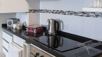 Una cocina moderna con electrodomésticos de acero inoxidable, encimera negra y salpicadero de azulejos.
