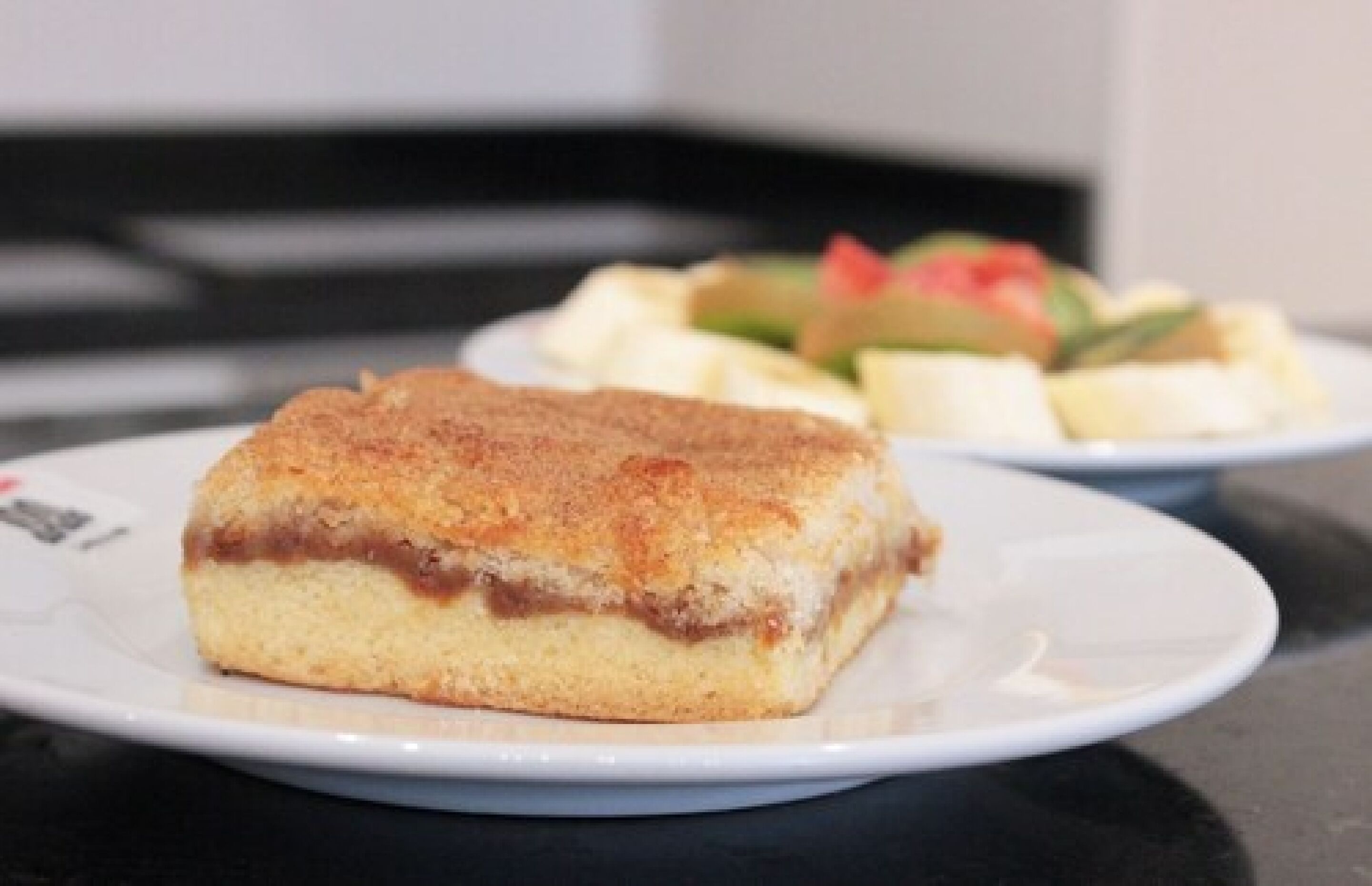 A dessert on a plate with a slice of cake and a side of fruit.