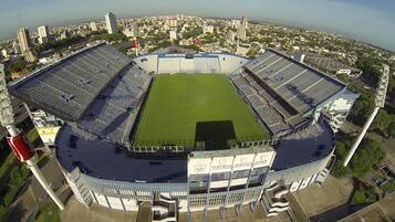 A stadium with a central field surrounded by tiered seating, large advertising banners, and a prominent tower structure.