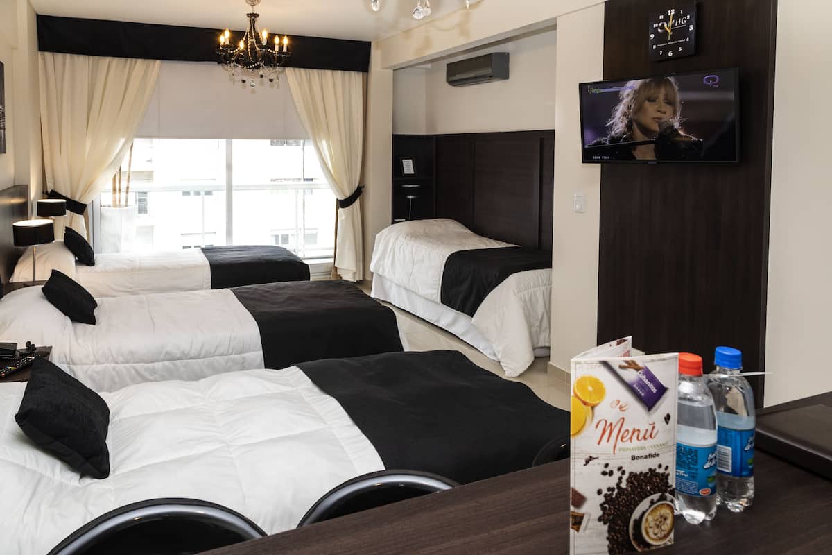 A hotel room with two beds, a TV, a minibar, and a view of the city.
