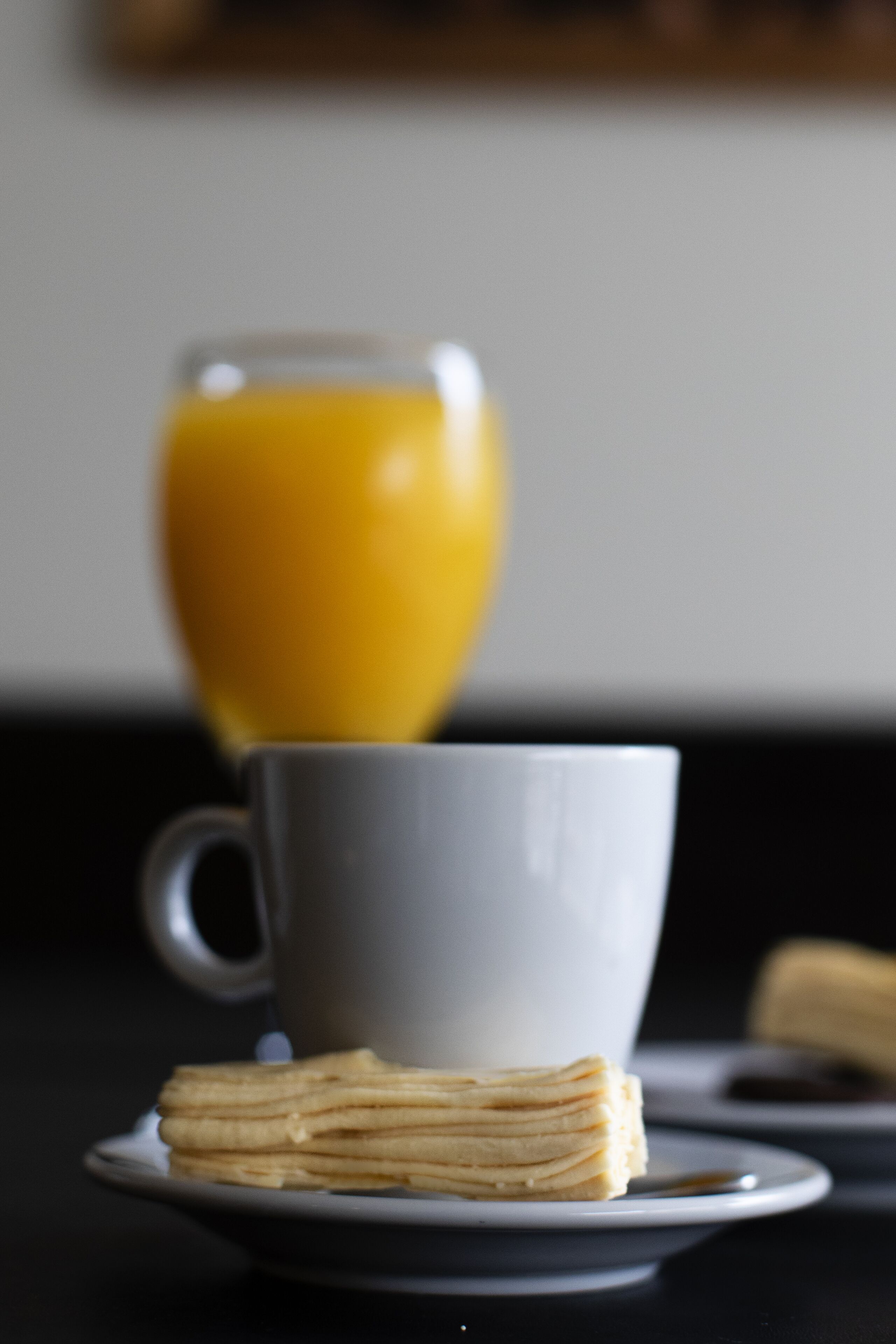 Un desayuno con una taza y una pila de tortitas en un plato.