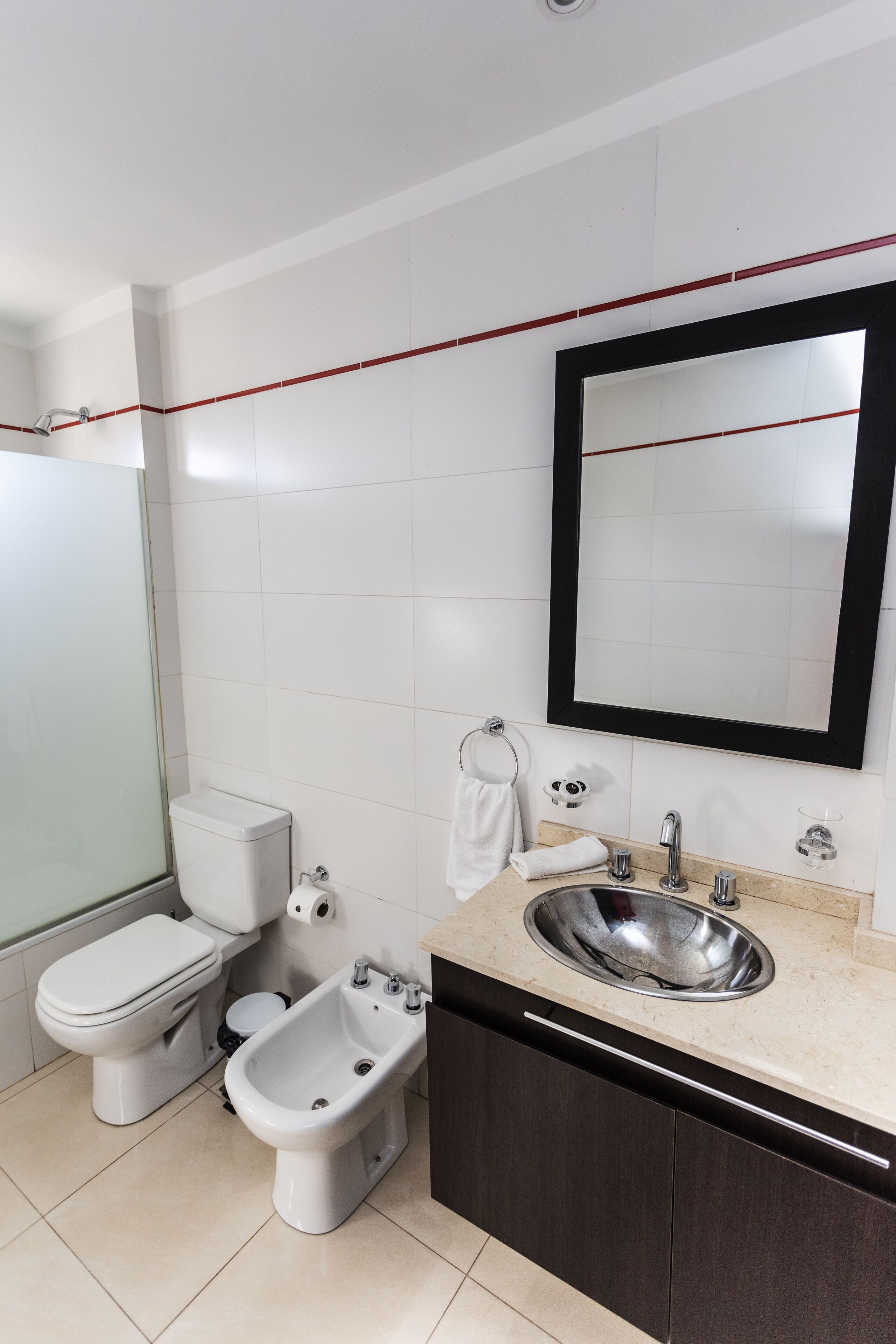 Een moderne badkamer met toilet, bidet, wastafel en spiegel.