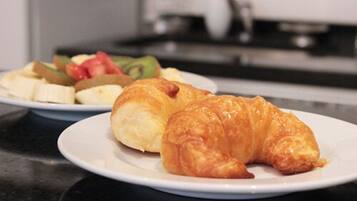 Eine Küchenarbeitsplatte mit einer Platte Croissants und einer Platte Obst.