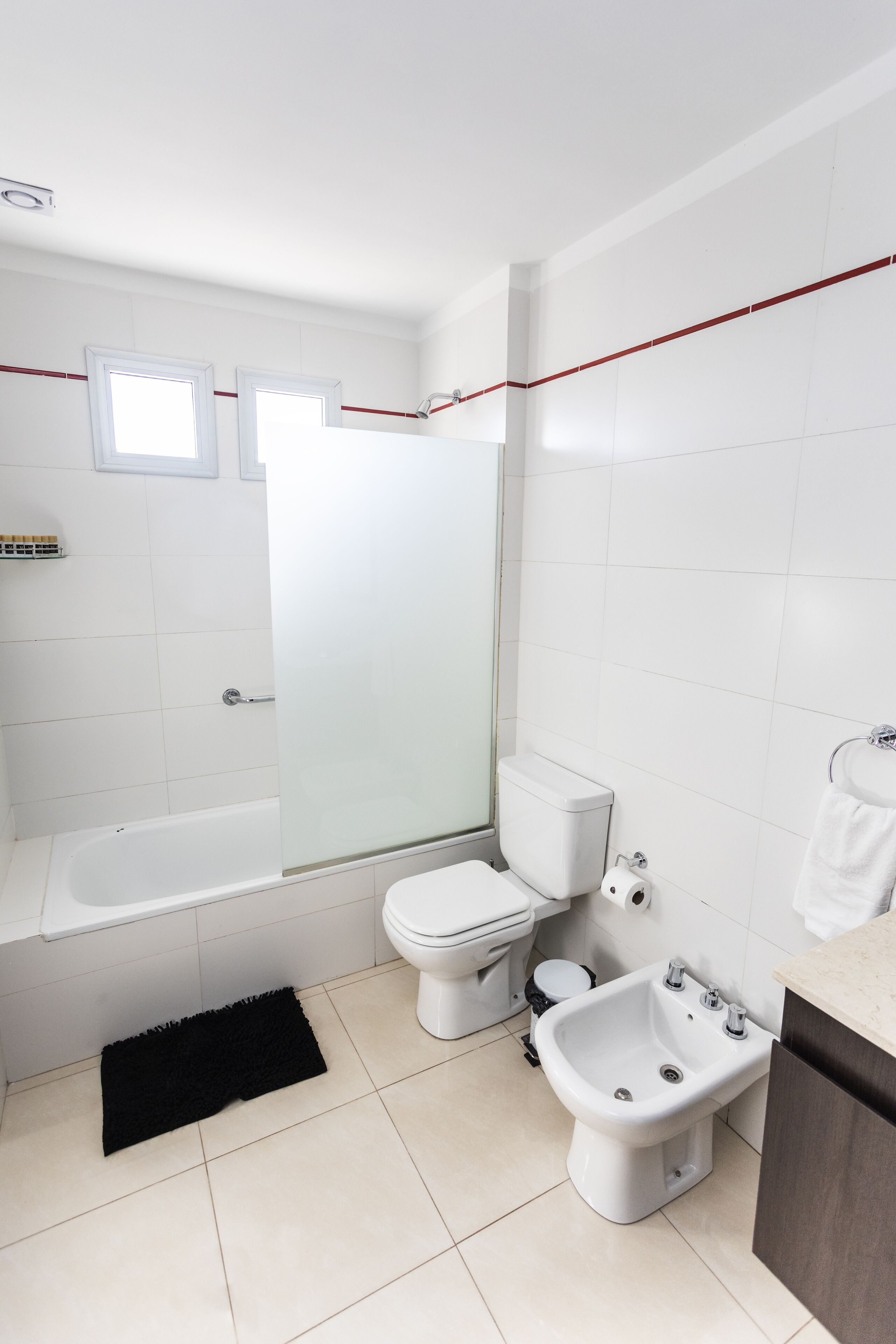 Une salle de bain moderne équipée d’une baignoire, de toilettes, d’un bidet et d’une douche à parois de verre.
