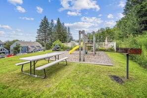 A playground with a slide, a picnic table, and a mailbox.