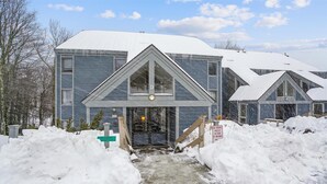 Una hilera de casas de dos pisos con techo nevado y un sendero que lleva a la entrada.
