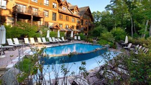 A pool area with lounge chairs and umbrellas, surrounded by a wooden building with balconies. - BEST Ski-in / ski-out in Tremblant!!!  CHIC chalet overlooking ski slopes!
   
  (Mont-Tremblant)