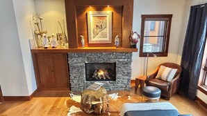 A cozy living room with a stone fireplace, a leather sofa, and a wooden coffee table. - BEST Ski-in / ski-out in Tremblant!!!  CHIC chalet overlooking ski slopes!
   
  (Mont-Tremblant)