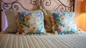 Ein Bett mit einer gesteppten Decke und zwei Kissen mit Blumenmuster.