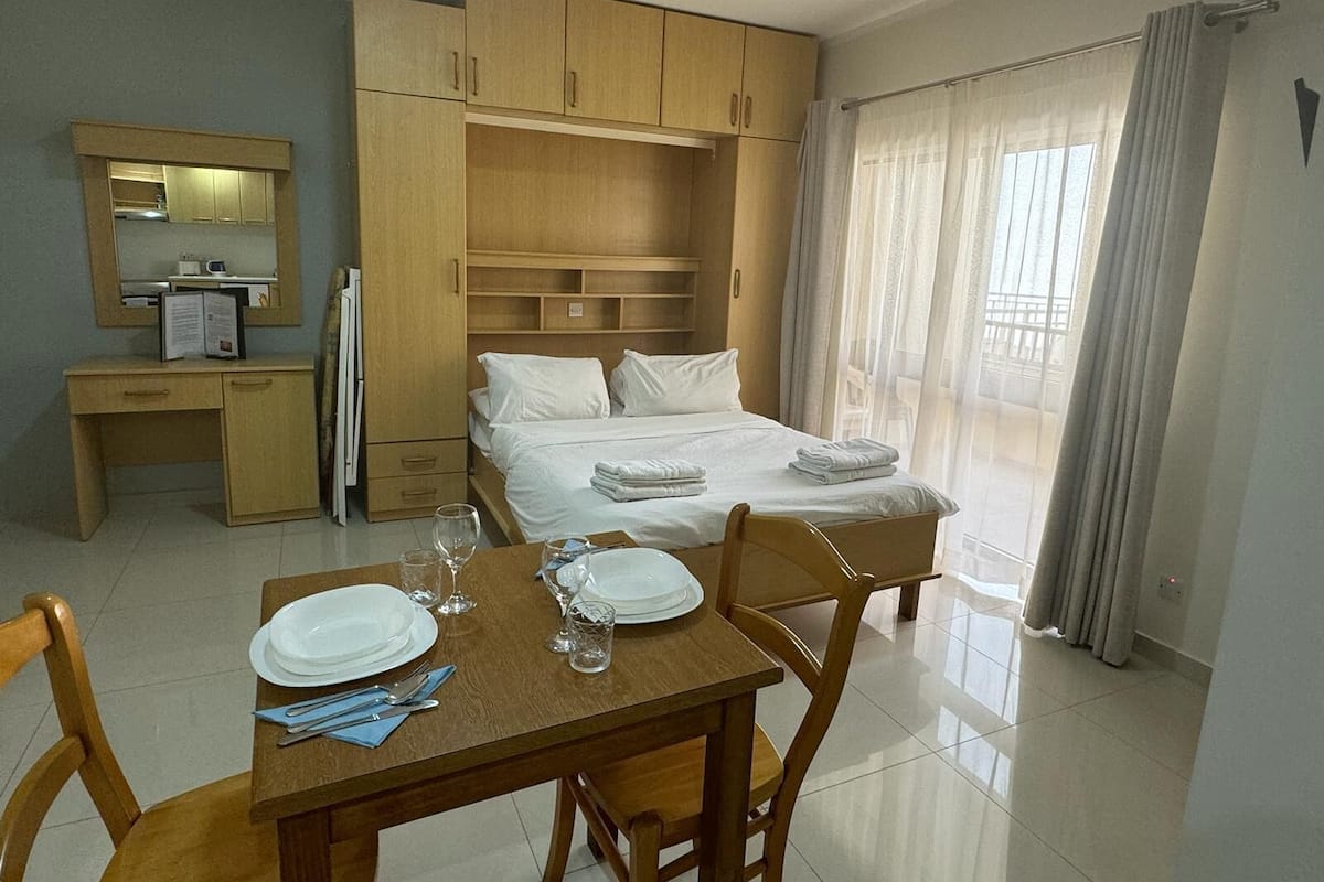 Una camera d'albergo con un letto, una scrivania, una sedia e un tavolo da pranzo per due persone.