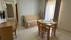 A compact living space with a dining area, a bed, and a TV. - Triton (St. Paul's Bay)