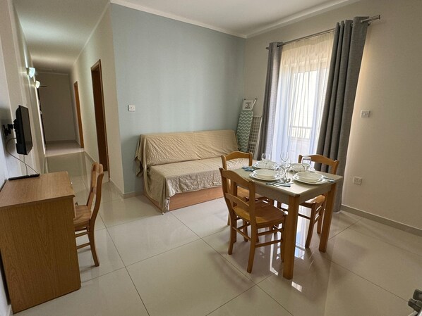 A compact living space with a dining area, a bed, and a TV. - The Triton (St. Paul's Bay)