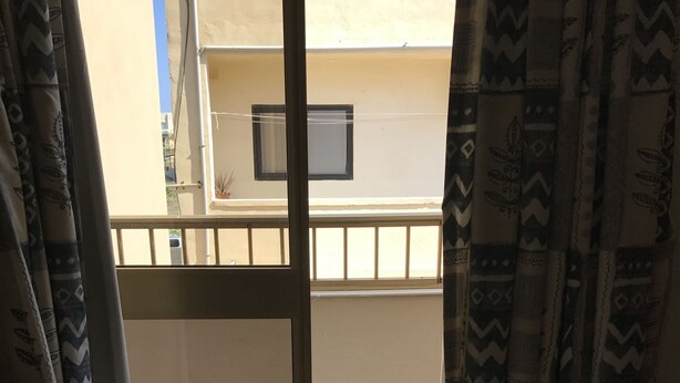 A room with a sliding glass door leading to a balcony. The balcony has a tiled floor and a railing. - The Triton (St. Paul's Bay)