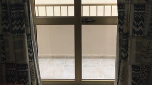 A room with a large window, patterned curtains, and a tiled floor. - The Triton (St. Paul's Bay)