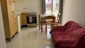 A compact living space with a kitchenette, a dining area, and a red sofa. - The Triton (St. Paul's Bay)