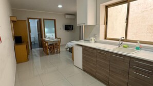 A modern kitchen with a dining area, a built-in dishwasher, and a window with a view. - Triton (St. Paul's Bay)