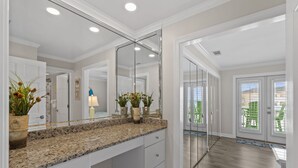 Ett modernt badrum med en bänkskiva i granit, en stor spegel och krukväxter.