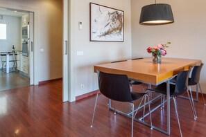 Ein Essbereich mit Holztisch, schwarzen Stühlen, einer Blumenvase und einer Pendelleuchte.