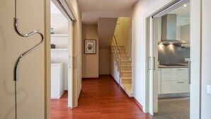 A modern interior with a wooden floor, a staircase, and a kitchen area. - Tessa - Habitat Apartments (Barcelona)