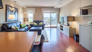 A modern living room with a wooden dining table, a sofa, and a TV. - Tessa - Habitat Apartments (Barcelona)