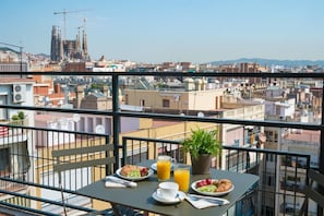 Ein Balkon mit Frühstücksangebot mit Blick auf eine Stadtlandschaft mit Gebäuden und einem Baukran.