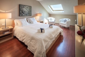 Ein Hotelzimmer mit einem großen Bett, zwei Nachttischen, einem Schreibtisch, einem Stuhl, einem Oberlicht und einem Bild an der Wand.