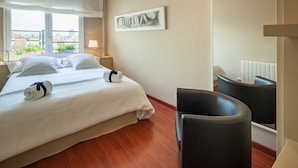 A hotel room with a bed, two bedside tables, a chair, a large window, and a painting on the wall. - Tessa - Habitat Apartments (Barcelona)