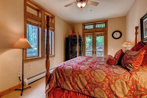 Un dormitorio con una cama grande, una lámpara de pie, un calentador y una ventana que da a vistas de árboles.
