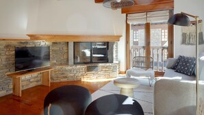 A cozy living room with a stone fireplace, a flat-screen TV, and comfortable seating.