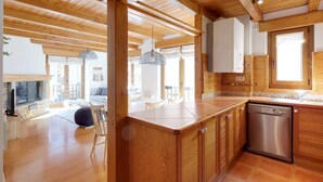 A modern kitchen with wooden cabinets, a dishwasher, and a dining area with a table and chairs.
