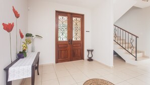 A spacious entrance with a wooden door, a staircase, and a dining area with a table and chairs.