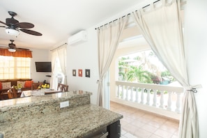 Relax in this open-plan living area with a kitchen counter, dining space, and large window offering a view of the outdoors.