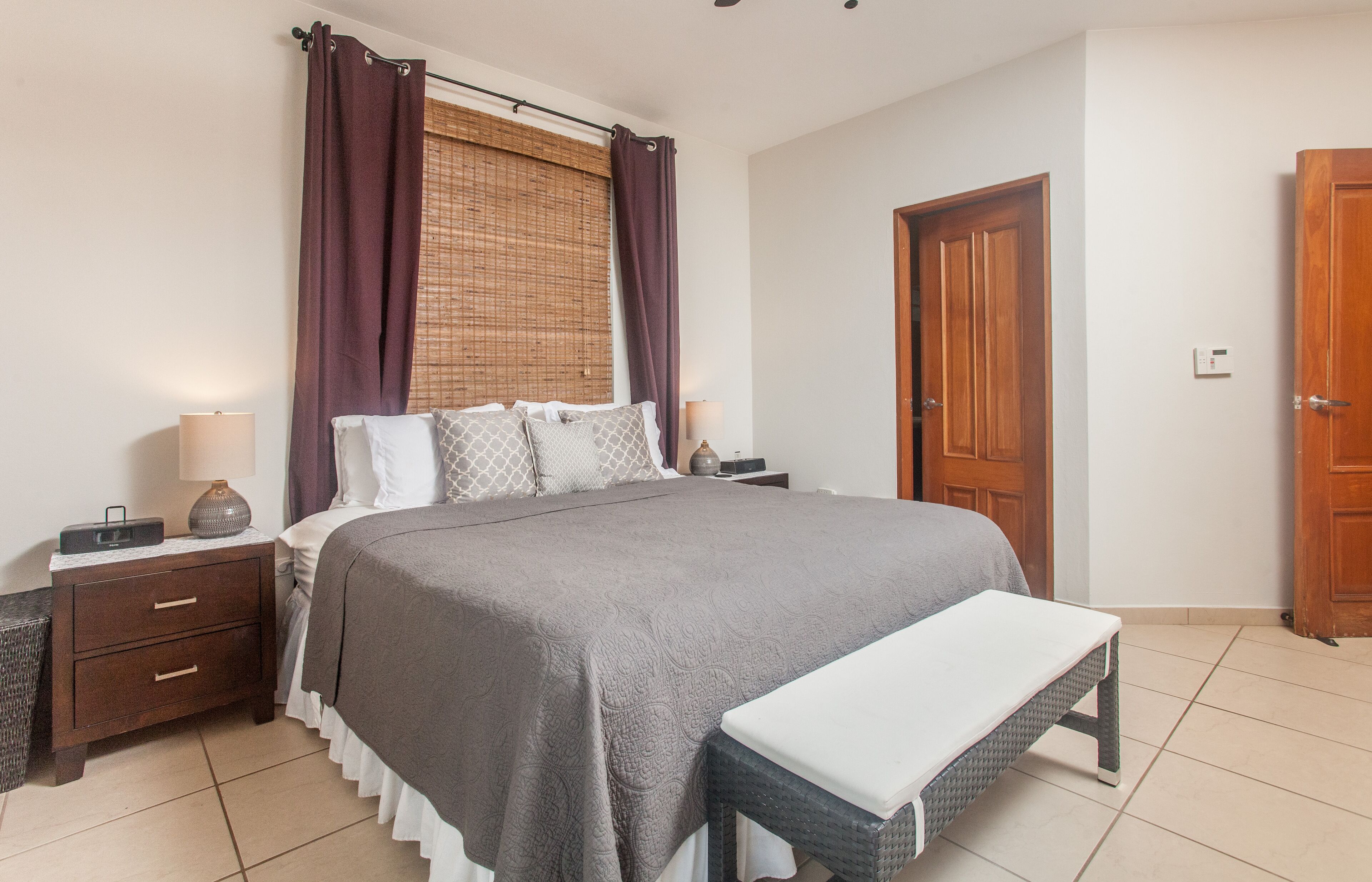 A neatly arranged bedroom with a large bed, bedside tables, a bench, and a wardrobe.