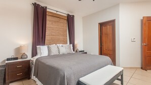 A neatly arranged bedroom with a large bed, bedside tables, a bench, and a wardrobe.