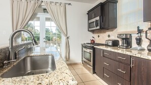 A modern kitchen with granite countertops, stainless steel appliances, and dark wooden cabinets.