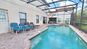 Un área de piscina con sillones reclinables y un patio cubierto.