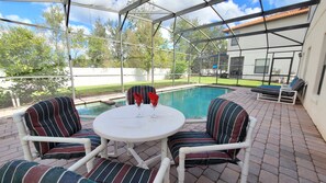 A covered patio with a pool, outdoor seating, and a view of the backyard. - Executive Home in Gated Community w pool spa, games room, close to shops (Clermont)