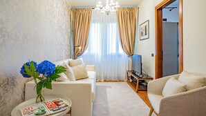 A living room with a sofa, a coffee table with magazines, a TV, and a door leading to another room. - Ca' Del Monastero 8 Collection (Venice)