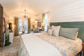 A bedroom with a large bed, a dresser, a chair, a desk, and a chandelier.