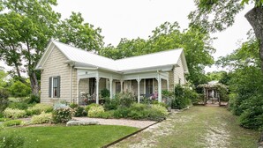 A two-story house with a covered porch and a garden. - Forget Me Not | Beautiful & Historic | Amazing Outdoor Space (Fredericksburg)