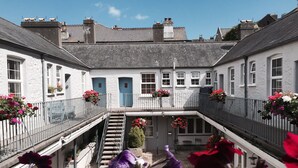 En traditionel hvid bygning med en central trappe, flere vinduer og blomsterkasser.