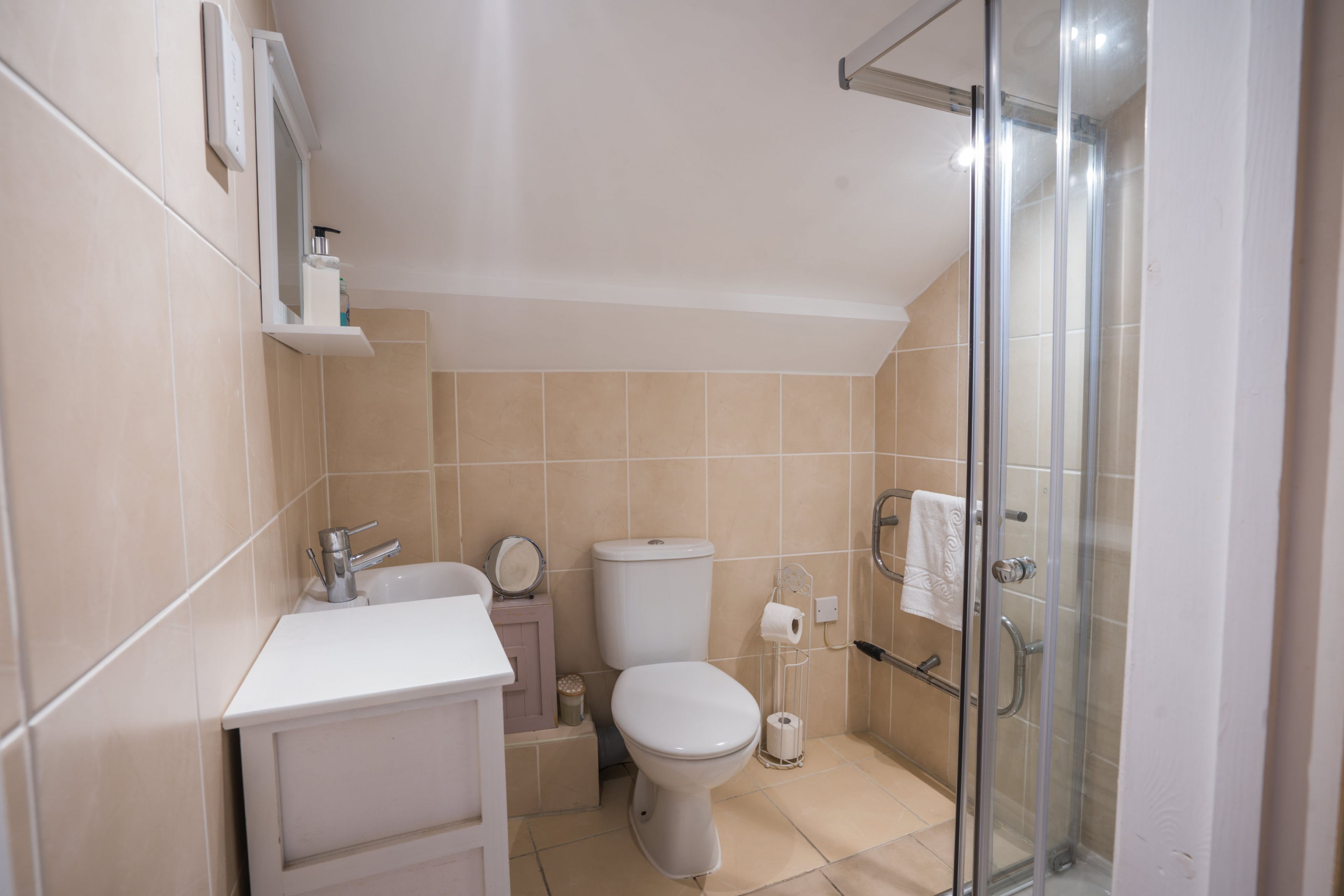Et moderne badeværelse med toilet, håndvask og glasbrusekabine.