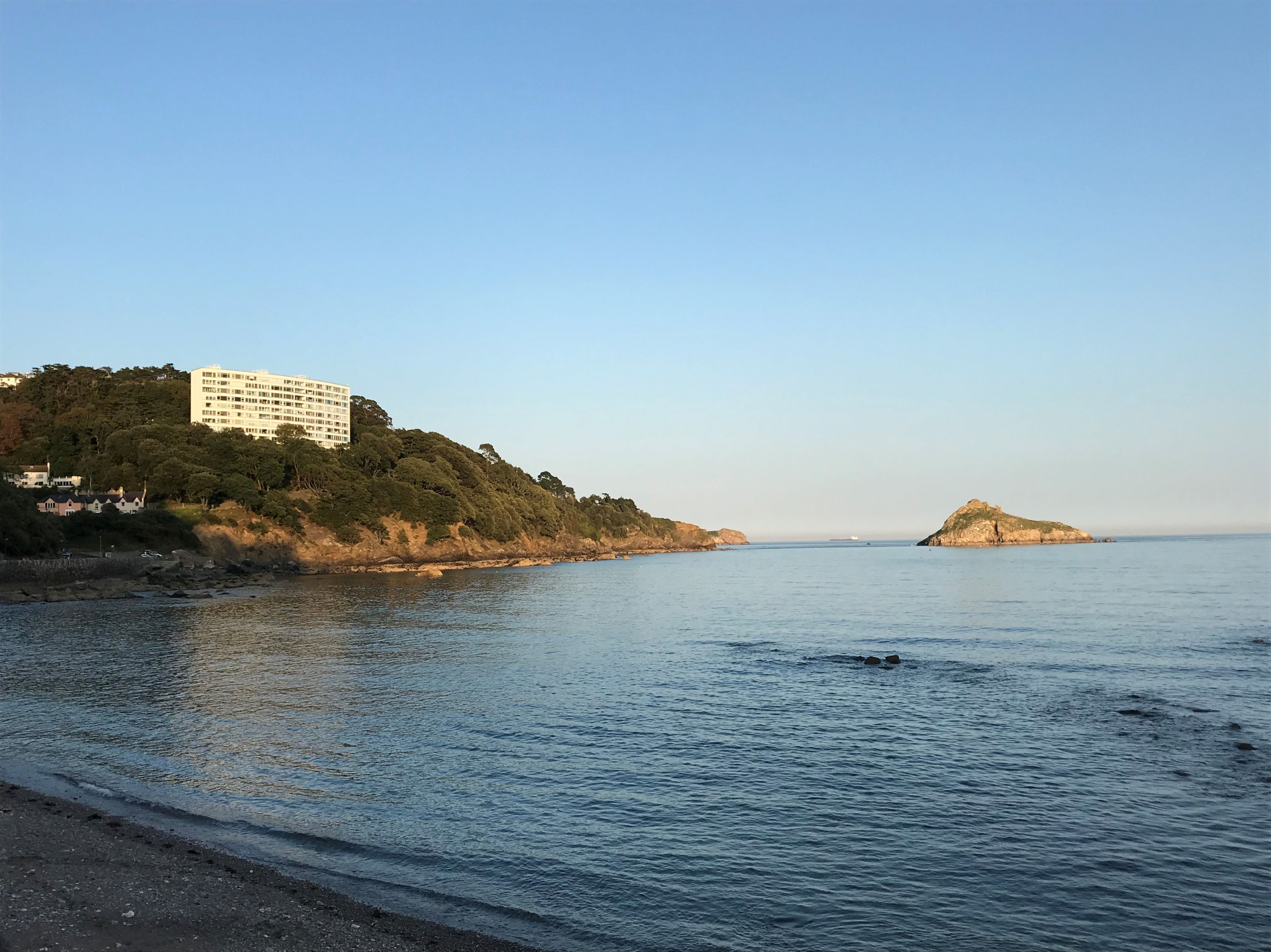 A coastal scene with a building on a hill and a small island in the distance.