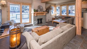 A spacious living room with a fireplace, large windows, and a cozy seating area. - Seasonal Pool | Pickleball | Hot Tub (Ketchum)