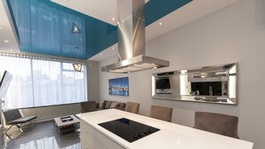 A modern kitchen with a central island, a stainless steel range hood, and a large mirror above the sink. - Duplex Loft with Private Terrace, Parc Avenue (Montréal)