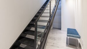 A modern staircase with a metal handrail and glass steps, leading to a landing with a bench. - Duplex Loft with Private Terrace, Parc Avenue (Montréal)