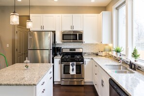 Una cocina moderna con armarios blancos, electrodomésticos de acero inoxidable y encimera de granito.
