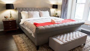 A neatly arranged bedroom with a large bed, bedside tables, a bench, and a patterned rug. - Urban Farmhouse - 3BR 2.5 BA (5 Beds) Near TG Park & Central to Everything! (St. Louis)
